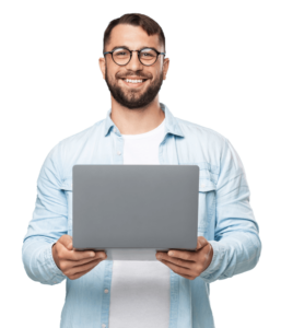 A man with a beard and glasses wearing a light blue shirt holds a laptop while smiling.