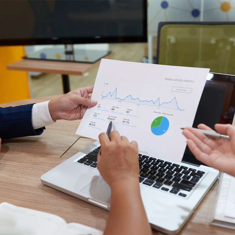 Two people reviewing a printed chart of website visitor statistics during a meeting at an SEO agency in Dallas.